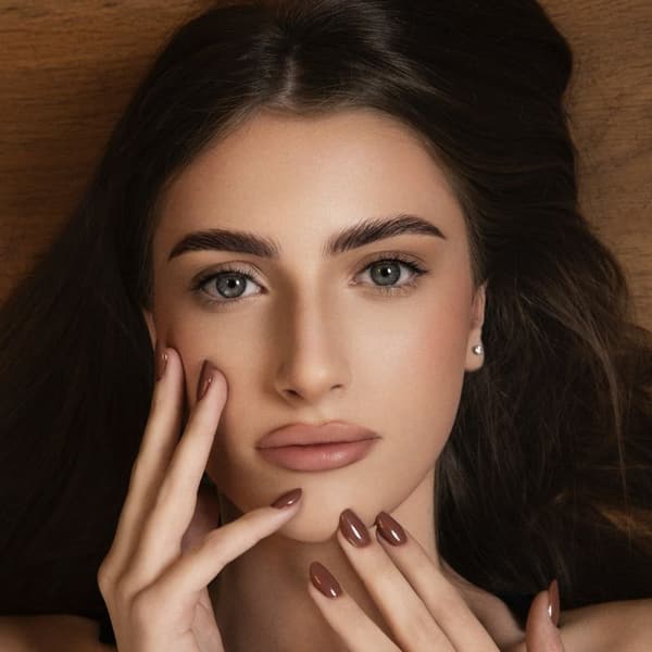 Portret modela sa istaknutim trepavicama i obrvama, ruka sa tamnim lakom na noktima uz lice